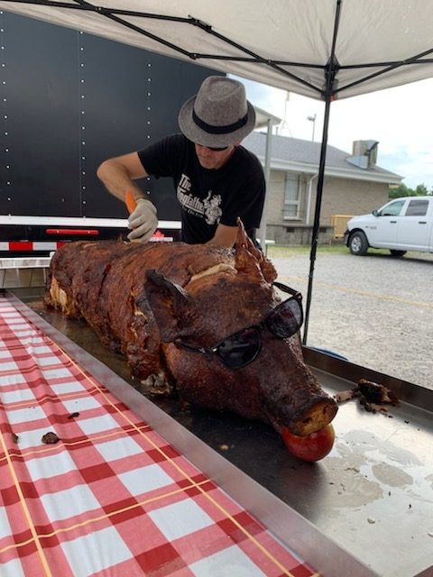 Carving rotisserie hog with sunglasses